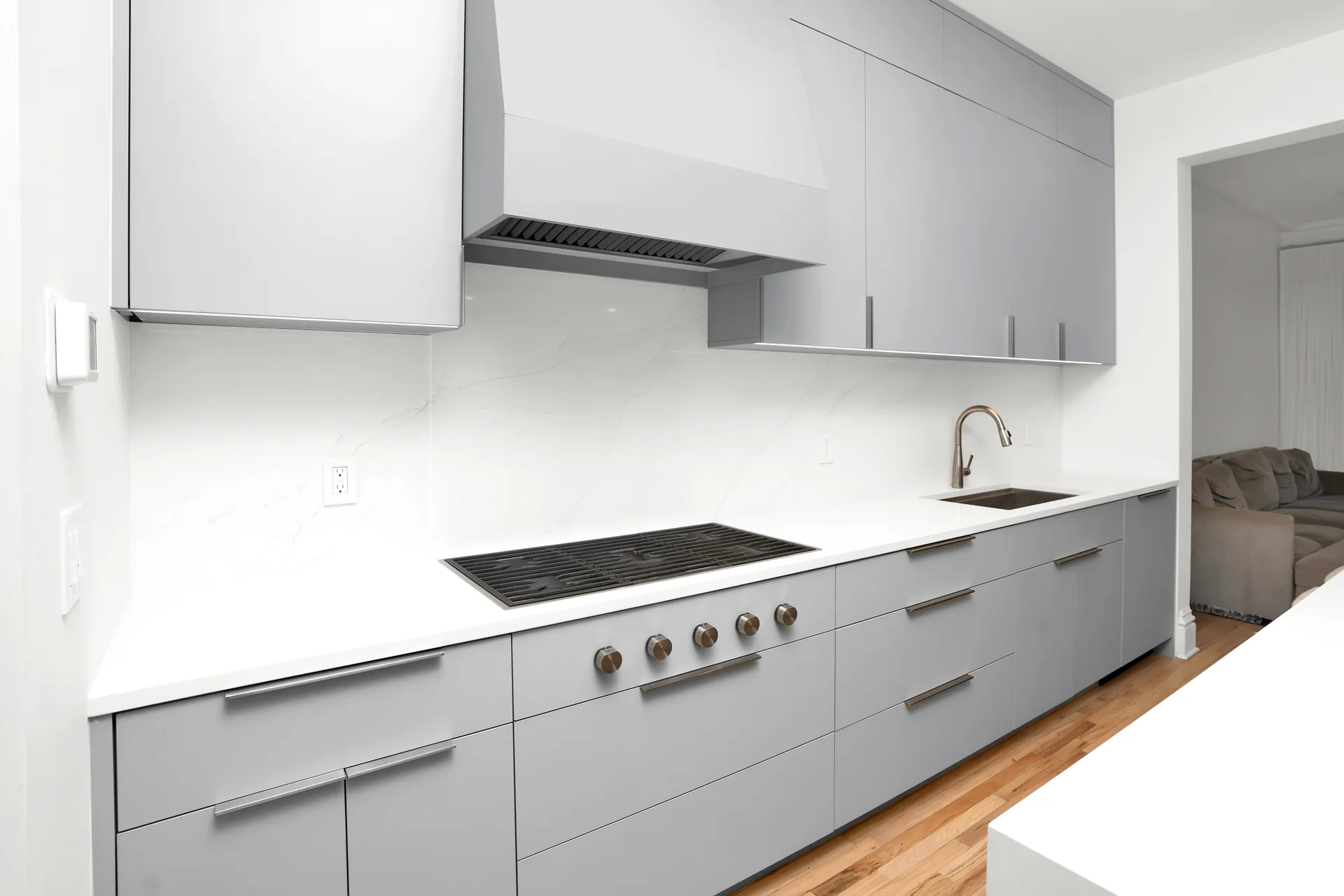 Cooktop above grey drawers and below the kitchen hood
