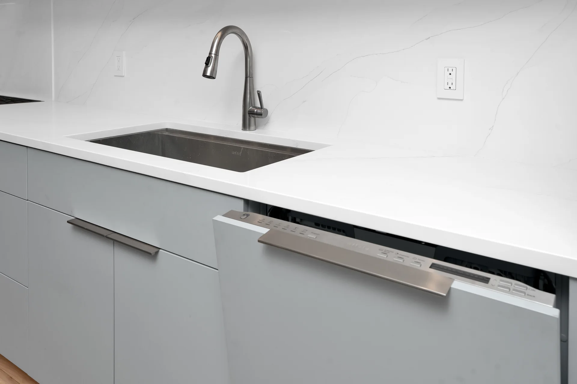 Kitchen sink and integrated dishwasher shown slightly open